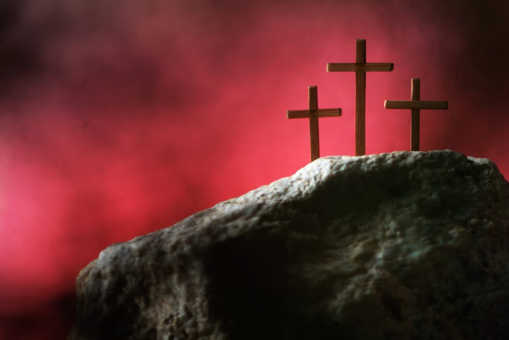 Three crosses against red sky on calvary hill background. Crucifixion, resurrection of Jesus Christ. Christian Easter holiday, Golgotha. He is Risen and Alive. Jesus is the reason for the season. Gospel, salvation.