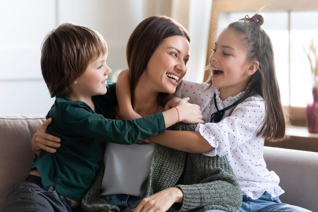 A woman and two children cuddle on a couch, embodying love and family bonding in a cozy setting.