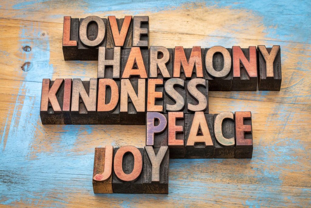 Wood type letterpress blocks arranged to spell “Love” highlighting concepts of harmony, kindness, peace, and joy.