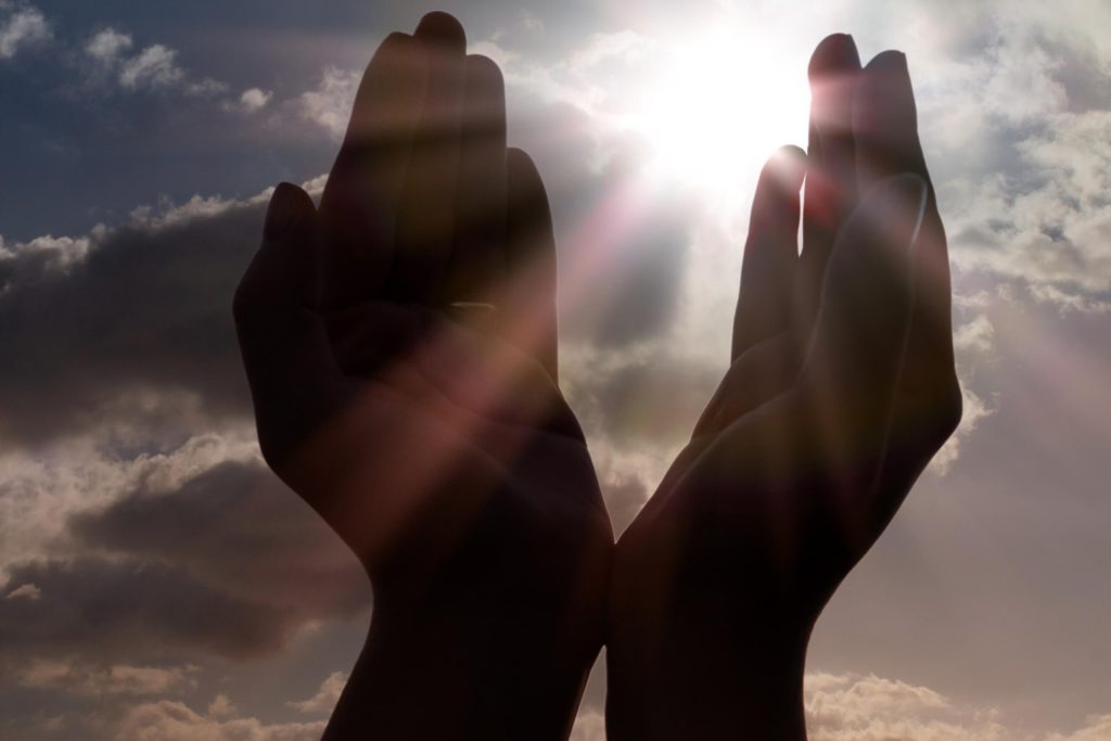 Uplifted hands towards the sun, symbolizing love and hope in a bright moment.