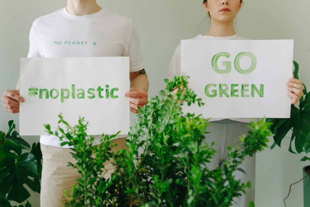 Two individuals hold a placard promoting #nonplastic and "GO GREEN," advocating for environmental sustainability.